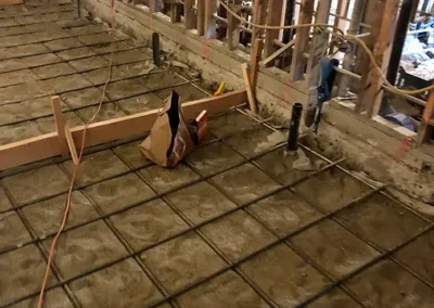 Network of black plumbing pipes laid in a gravel trench, connecting at various angles, with some marked in red and blue.